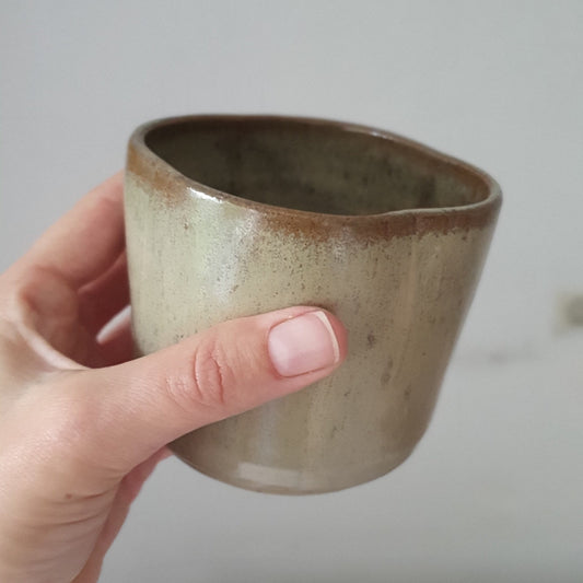 Zu sehen ist ein handgemachter Keramik-Becher in der Farbe Beige