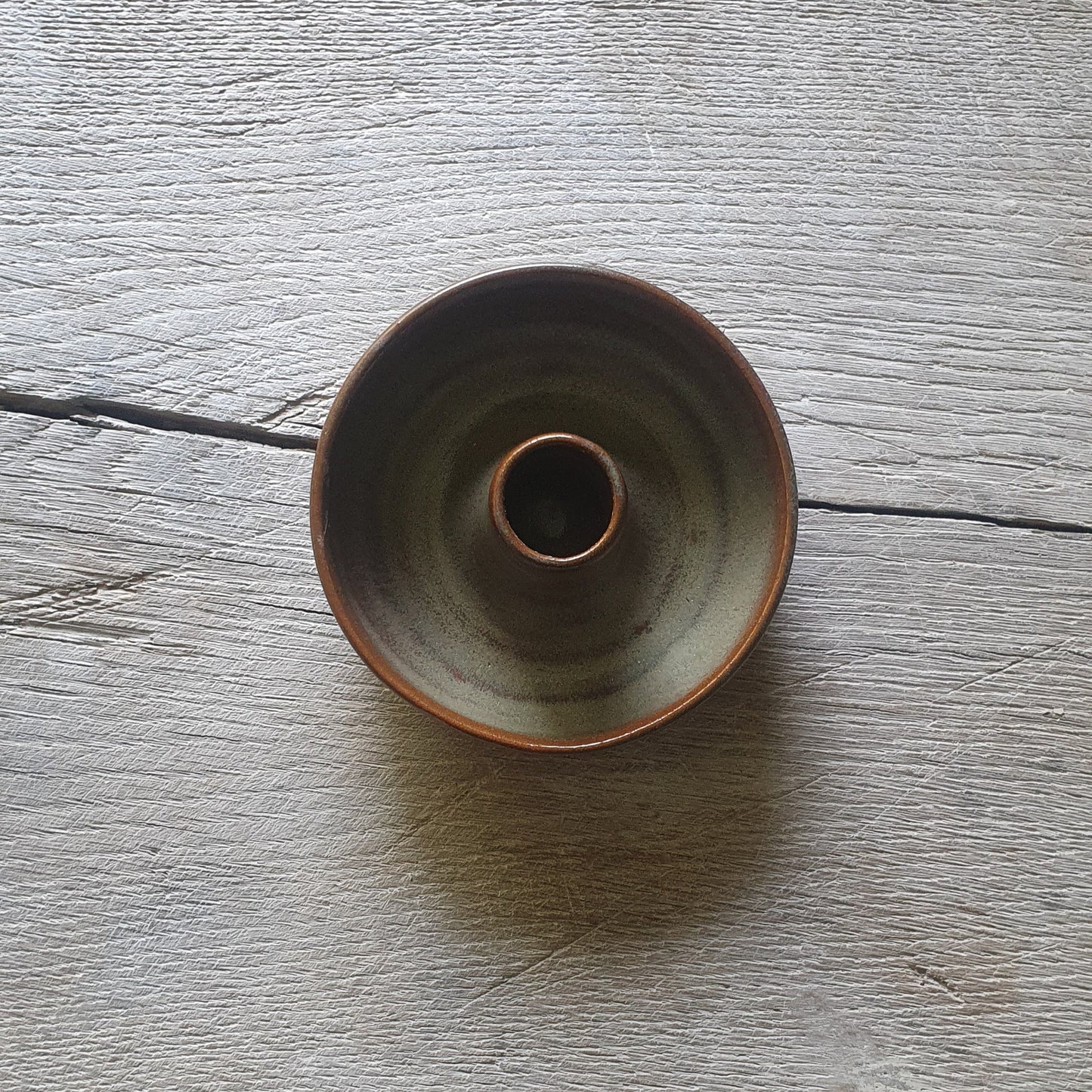 Zu sehen ist ein Kerzenständer in Grün/Braun Kastanie