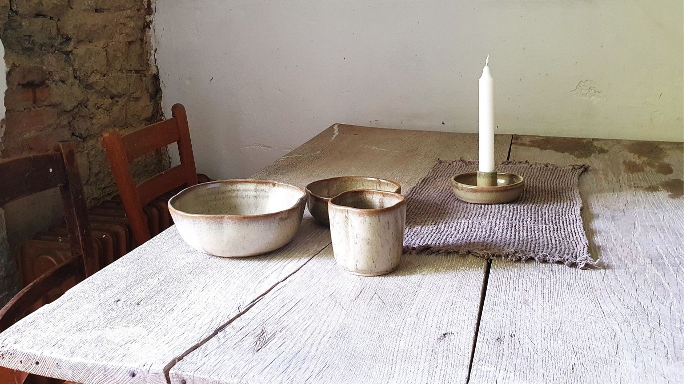 Zu sehen ist ein Holtisch mit handgemachtem Keramik-Geschirr.