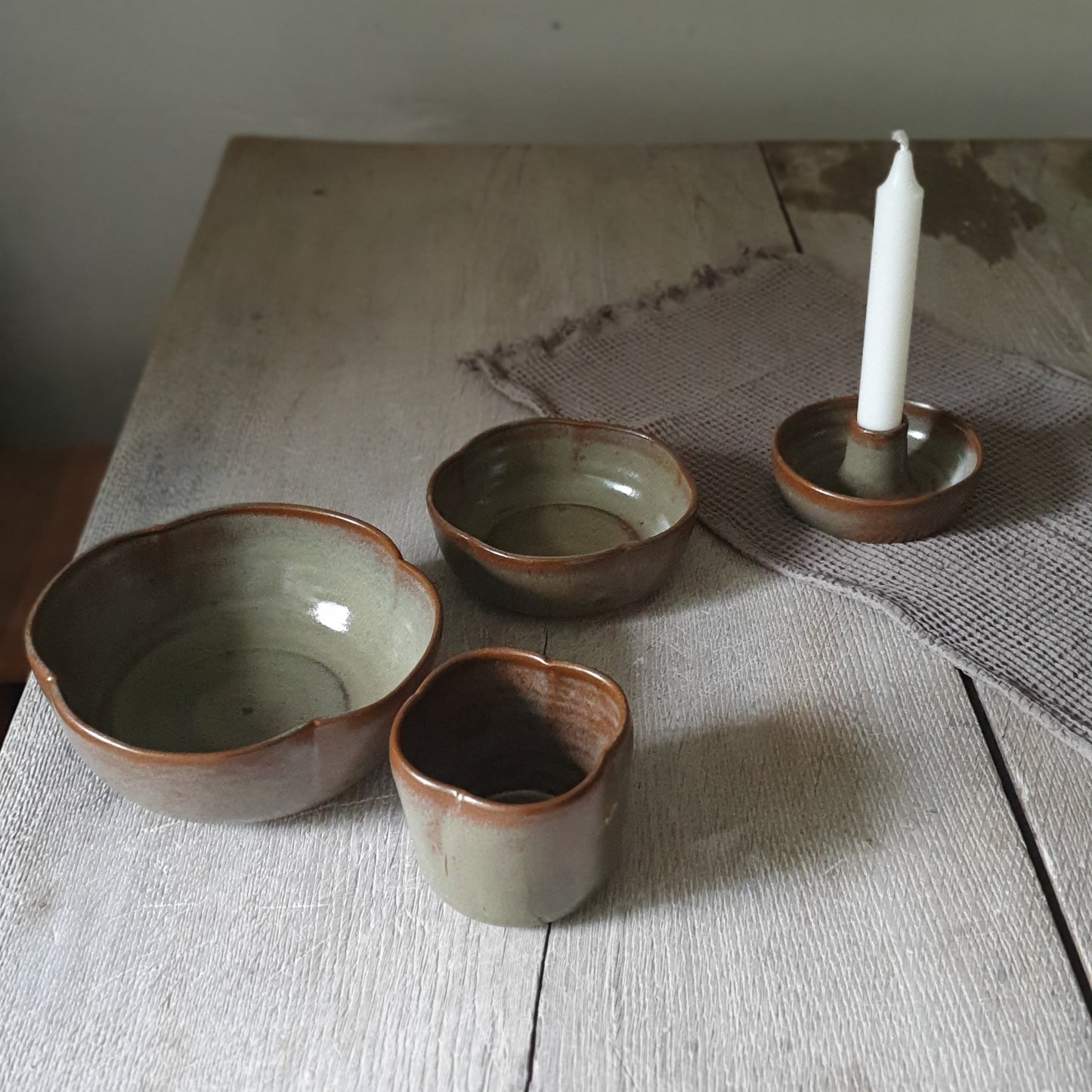 Zu sehen ist ein handgemachtes Keramiktisch-Set in der Farbe Grün/Braun von oben.
