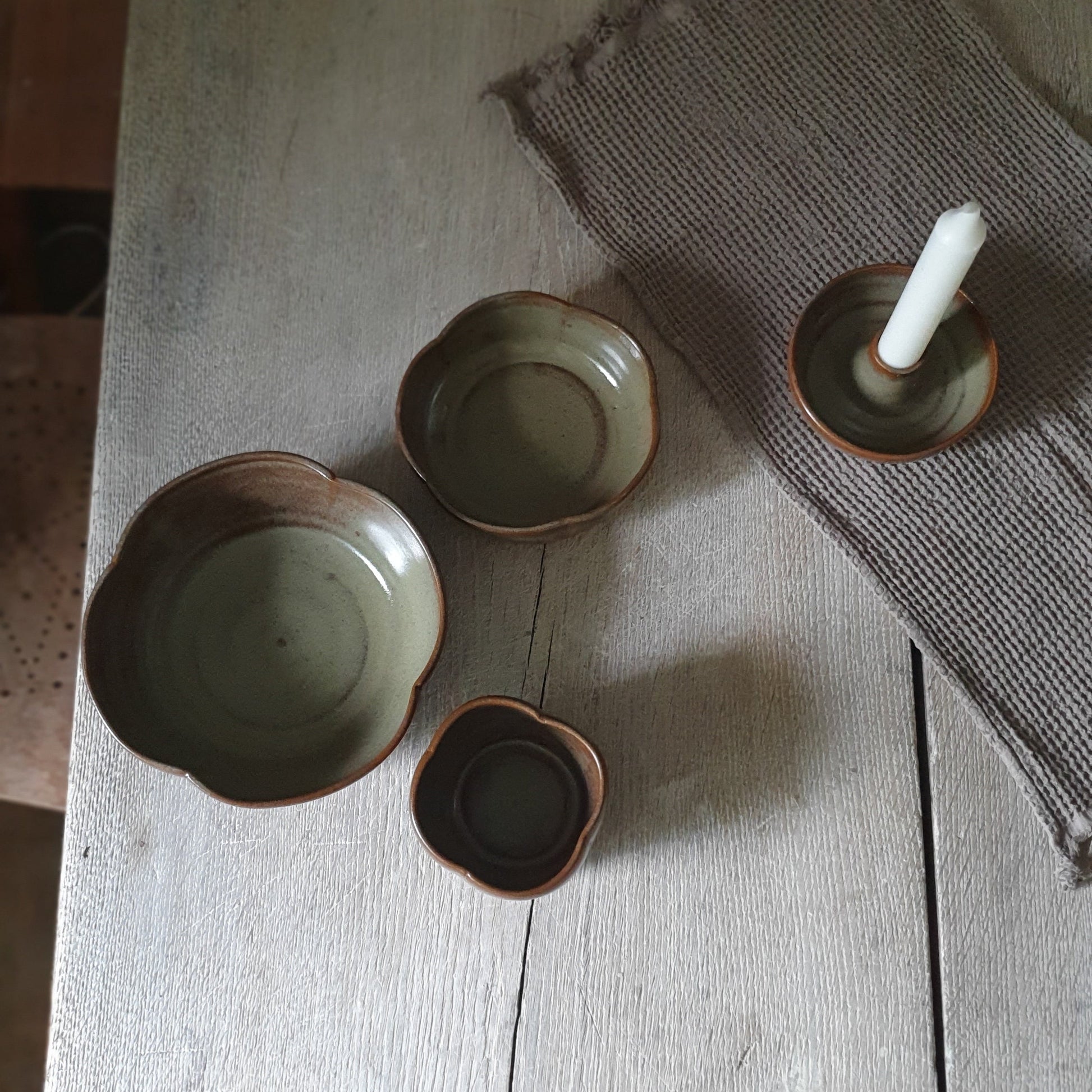 Zu sehen ist ein handgemachtes Keramiktisch-Set in der Farbe Grün/Braun von oben.
